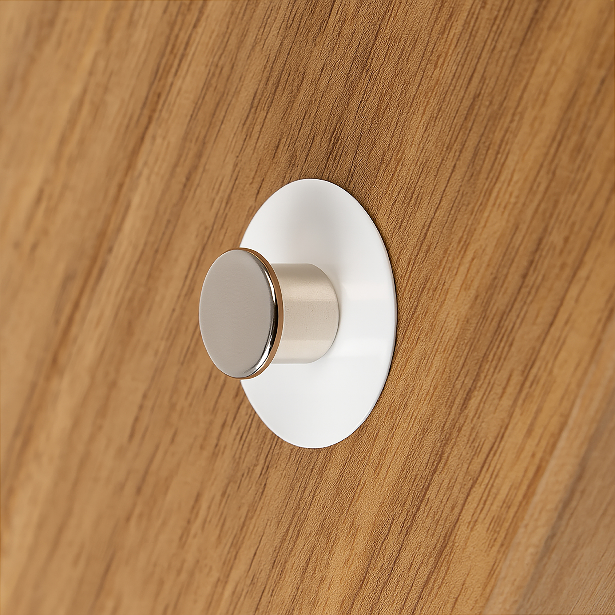 Weiße Haftplatte für Magnete selbstklebend Ø40x1mm geklebt auf eine Holzfläche mit einem Büromagneten auf der weißen Fläche